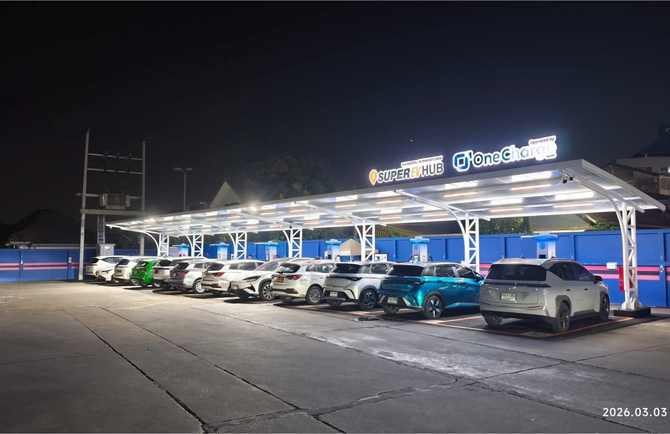 ป้าย Super EV Hub นนทบุรี พระราม 5 ที่ตั้งอยู่เหนือหัวชาร์จ Huawei Ultrafast 720kW มีรถ EV หลายคันจอดชาร์จอยู่ใต้หลังคาเวลากลางคืน